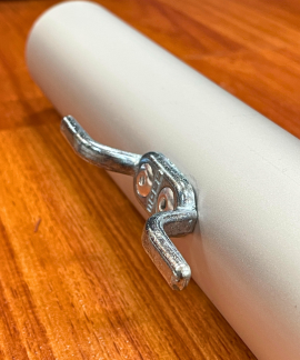 Metal clamp attached to a white cylindrical pipe