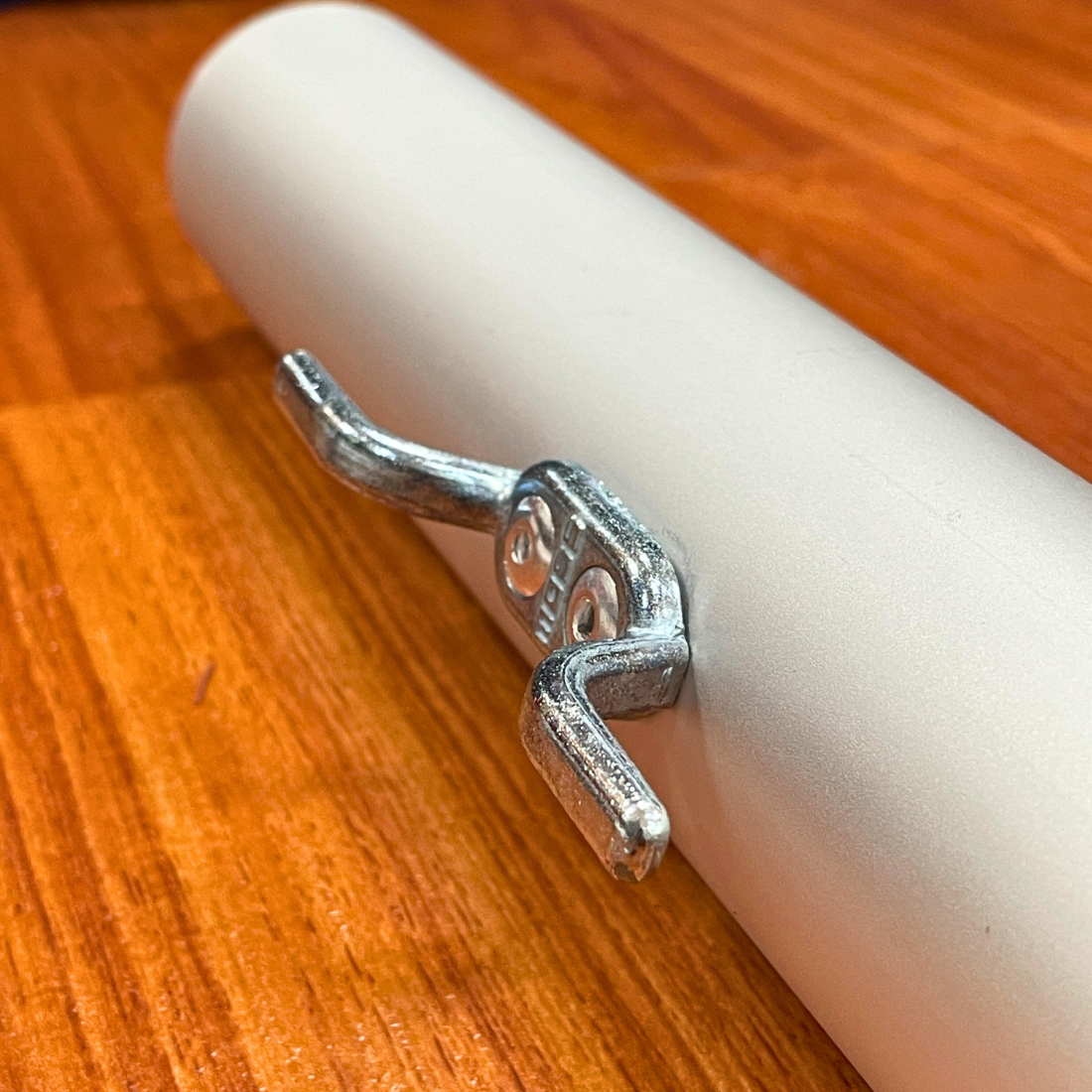 Metal clamp attached to a white cylindrical pipe