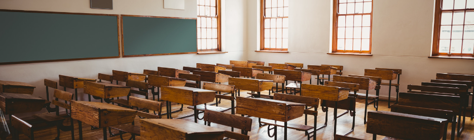 Empty classroom with wooden desks and chalkboard
