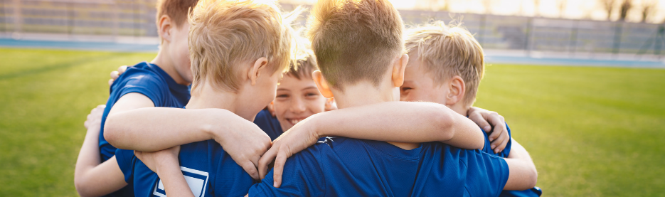 Young soccer team huddling on field