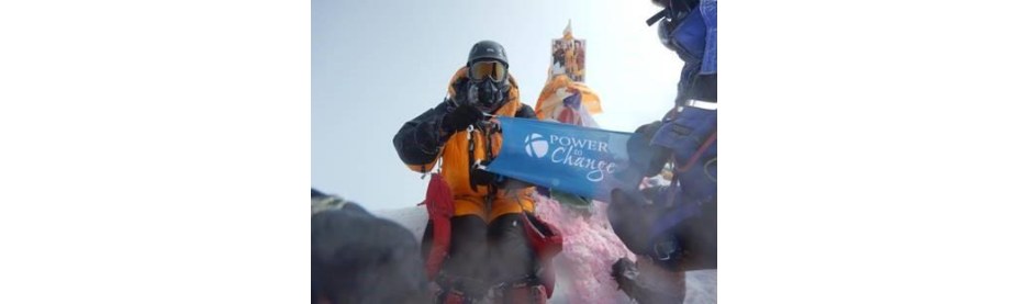 Climber holding Power to Change banner on snowy peak
