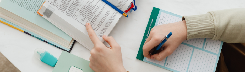 Student studying and taking notes with books